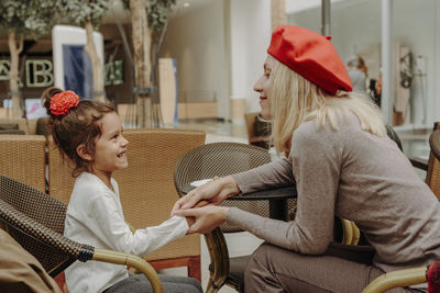 Mom and daughter holding hands in a coffee shop.