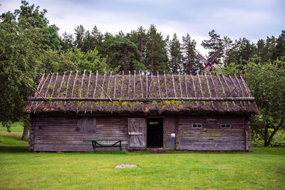 House and trees on field against sky