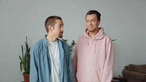 Gay couple standing by wall at home