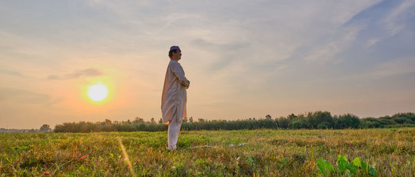 Man standing on field against sky during sunset