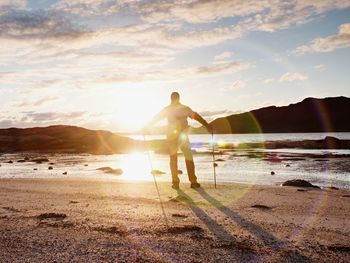 Walker watch spring daybreak over sea. hiker with backpack stand on sandy shore. hiking ambition.