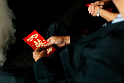 Midsection of man holding envelope while sitting on stage