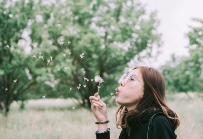Beautiful woman blowing dandelion at park