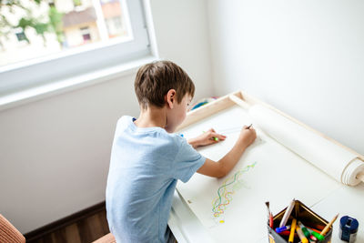 Boy sitting on table at home