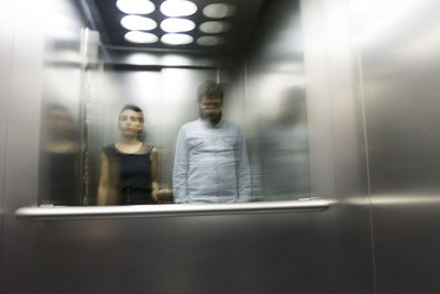 Reflection of man and woman on mirror in elevator