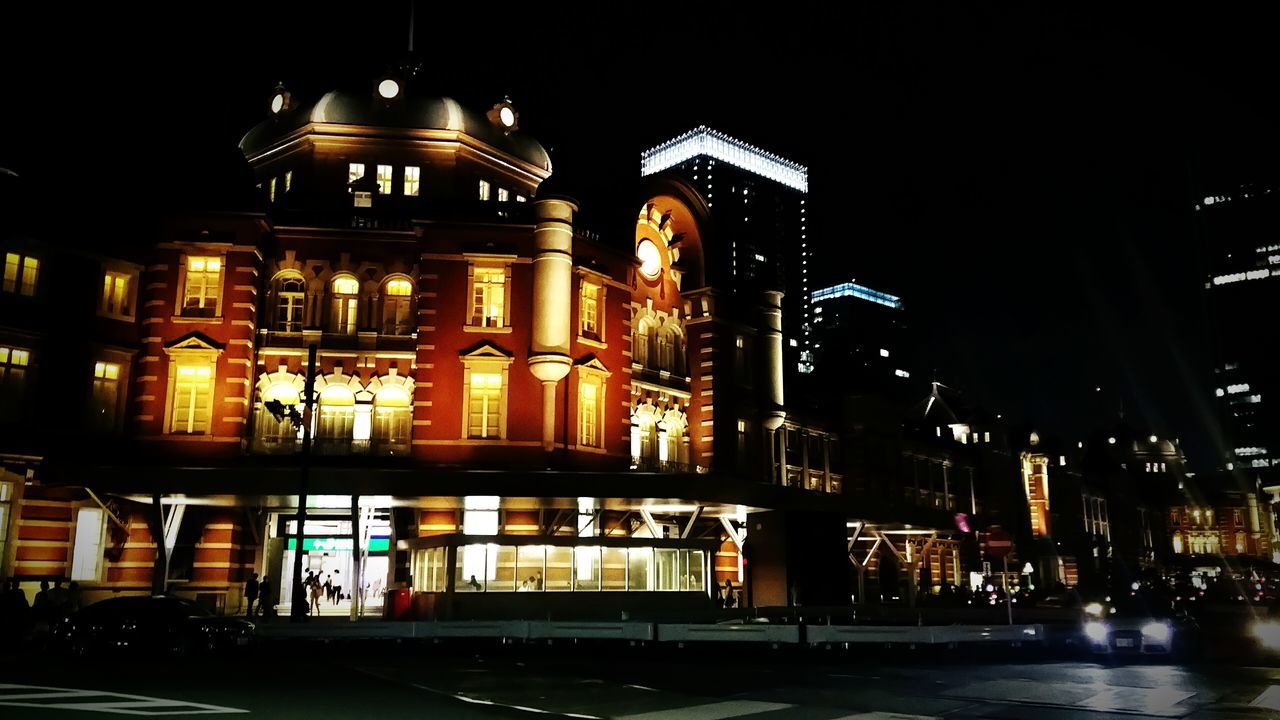 night, illuminated, building exterior, architecture, built structure, city, street, street light, building, city life, lighting equipment, residential building, incidental people, outdoors, light - natural phenomenon, residential structure, sky, city street, road, facade