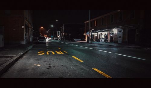 Road passing through illuminated city at night