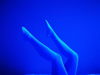 Low angle view of human hand against blue background