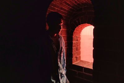 Thoughtful man standing by window in darkroom