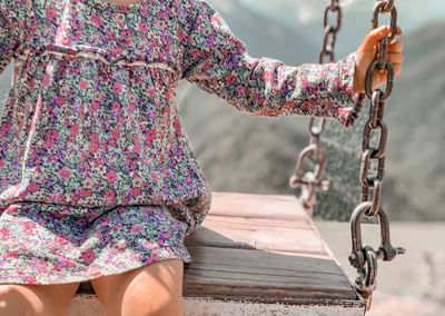 Midsection of woman sitting on swing outdoors