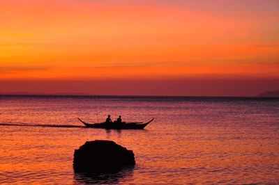 Silhouette person in sea against sky during sunset