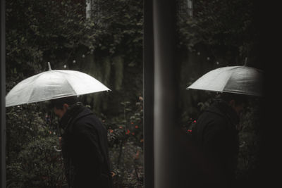 Man holding umbrella seen through doorway