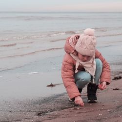 Full length of girl crouching on beach