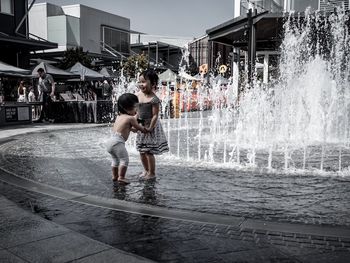 Full length of a boy splashing water fountain