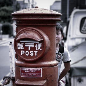 Boy hiding behind mailbox in city