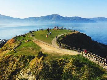 People on mountain against sea and sky