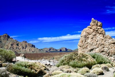 Rock formations on landscape against blue sky