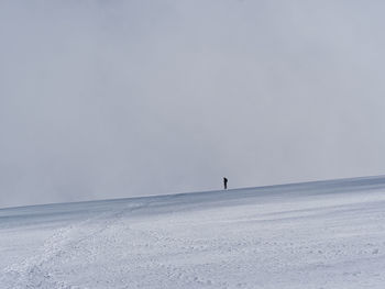 People on snow covered land against clear sky