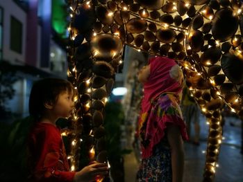 Rear view of boy standing by illuminated christmas lights