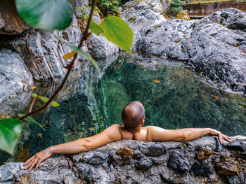 Rear view of shirtless man on rock