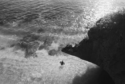 High angle view of silhouette man with surfboard in sea