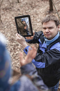 High angle view father showing digital tablet in forest