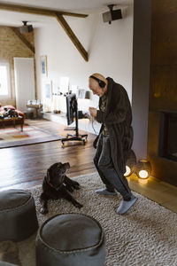 Senior man dancing while standing near dog on carpet at home