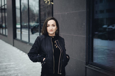 Portrait of young woman standing by building