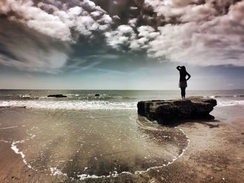 Scenic view of beach against cloudy sky