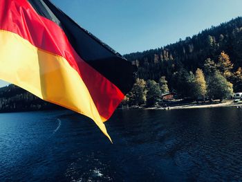 Red flag by lake against sky