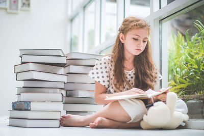 Girl reading book by window