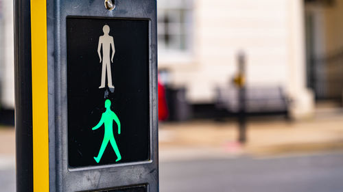 Pedestrian crossing sign on street with green man