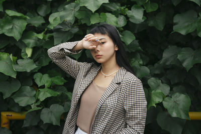 Portrait of young woman standing against plants