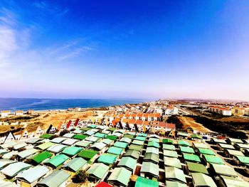 High angle view of townscape by sea against blue sky