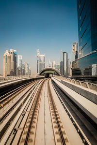 Railroad tracks in city against clear sky