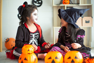 Smiling girls wearing costume sitting at home