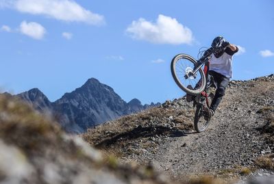 Low angle view of racer riding mountain bike downhill against sky