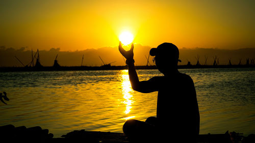 Silhouette man on beach against sky during sunset