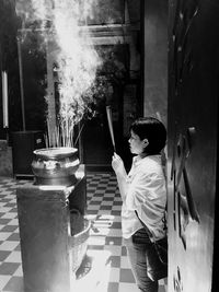 Side view of boy standing on glass against built structure