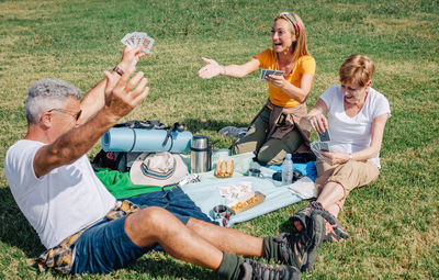 Senior man celebrating that he has won his family playing cards during an excursion