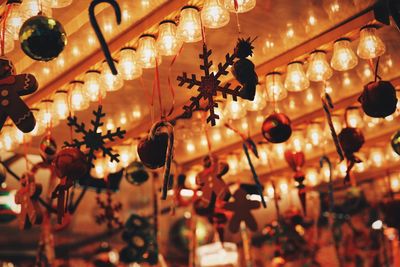 Low angle view of illuminated light bulbs and christmas decorations on ceiling