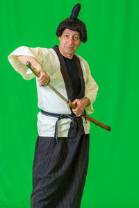 Portrait of man dressed as samurai against green background