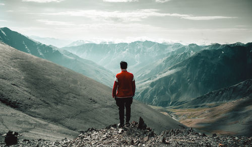 Rear view of man standing on mountain against sky