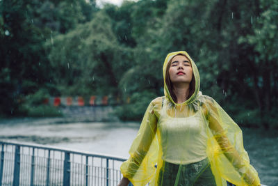 Young woman wearing raincoat while standing in rain