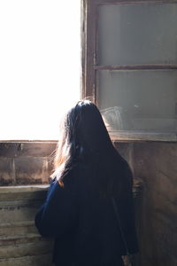 Rear view of woman standing by window