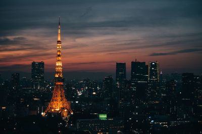 Illuminated buildings in city against sky at sunset