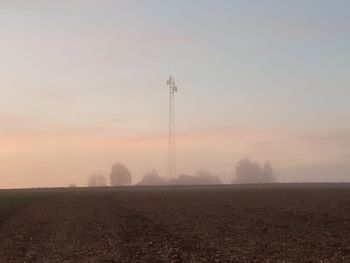 Electricity pylon on field against sky during sunset