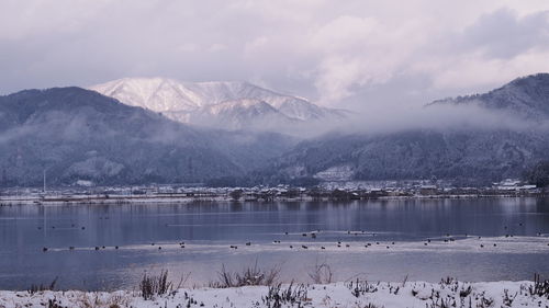 Scenic view of lake by snowcapped mountains against sky