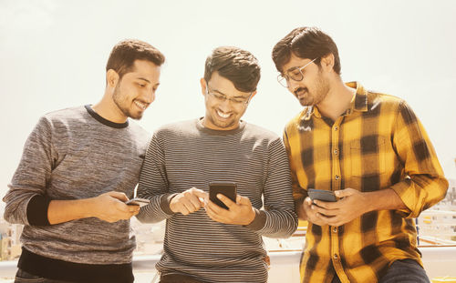 Group of young people watching mobile phone on terrace and laughing and having fun.