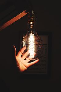 Close-up of hand holding illuminated light bulb